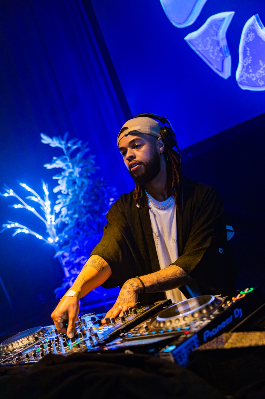 DJ performing beneath blue light at Corazón Winter Paradise