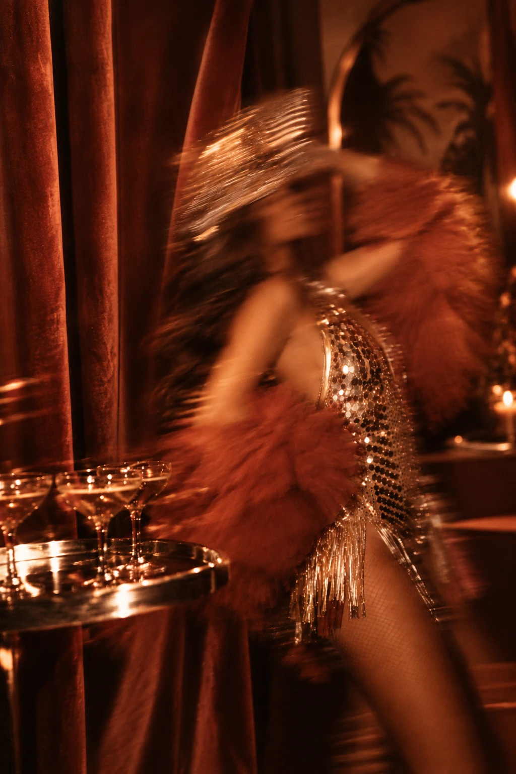 Blurred performer in gold and terracotta beside champagne glasses